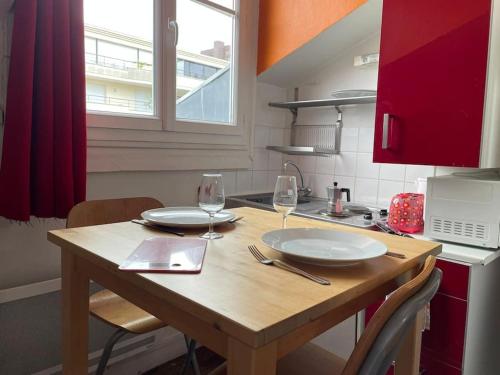 uma cozinha com uma mesa de madeira com 2 pratos e copos de vinho em Penthouse by Roland-Garros em Boulogne-Billancourt