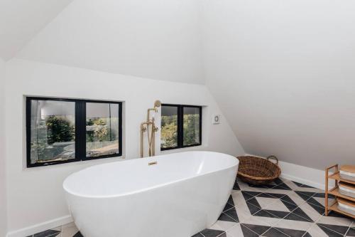 La salle de bains est pourvue d'une baignoire blanche et de fenêtres. dans l'établissement The Lakeside Viewing Gallery, à Shiplake