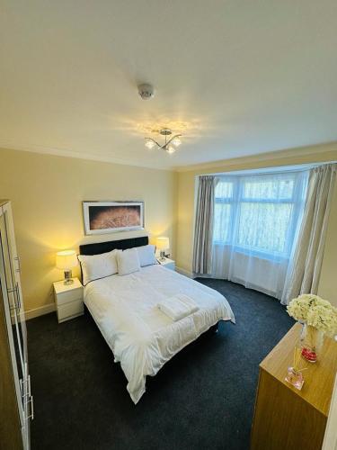 ein Schlafzimmer mit einem großen weißen Bett und einem Fenster in der Unterkunft 4 Bed Family Home in Woodford Green