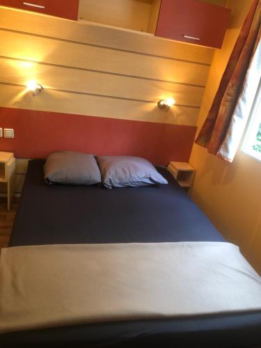 Bett in einem kleinen Zimmer mit zwei Kissen in der Unterkunft Camping Parc des Roches-Mobilhome in Saint-Chéron