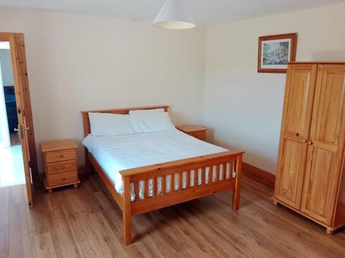 Schlafzimmer mit einem Bett und einem Holzschrank in der Unterkunft Willowfarmhouse in Milford