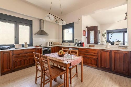 a kitchen with wooden cabinets and a table and chairs at 50 steps from the sea. in Gournes