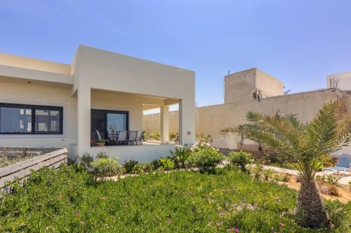 a house with a palm tree in front of it at 50 steps from the sea. in Gournes