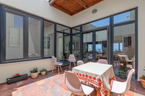 a room with a table and chairs and windows at 50 steps from the sea. in Gournes
