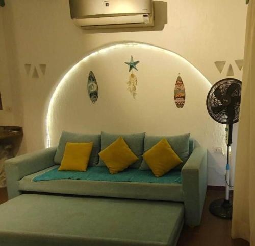 La Hacienda - Ras Sedr Chalet - Ras Sudr في رأس سدر: أريكة زرقاء مع وسائد صفراء في غرفة المعيشة