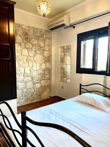 a bedroom with a bed and a stone wall at Sea and Stone Villa in Afitos
