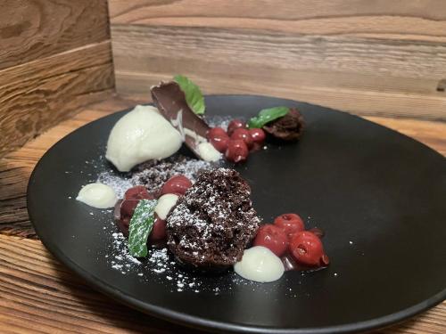 a black plate with food on a wooden table at Hotel Landhaus Tirolerherz in Sankt Ulrich am Pillersee