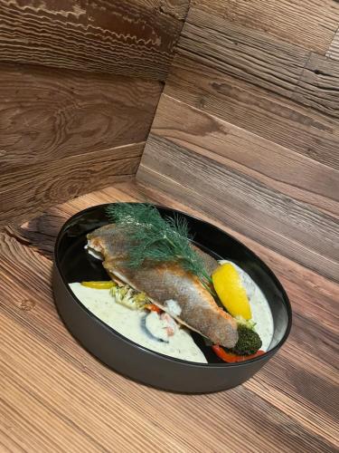 a plate of food with a fish and vegetables on a table at Hotel Landhaus Tirolerherz in Sankt Ulrich am Pillersee