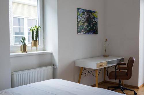 a bedroom with a bed and a desk and a window at Cozy City Apartment in Graz