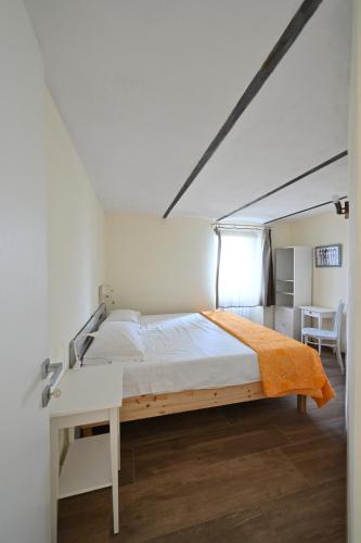 a white bedroom with a bed and a desk at CASCINA BINELLO appartamento B in Murazzano