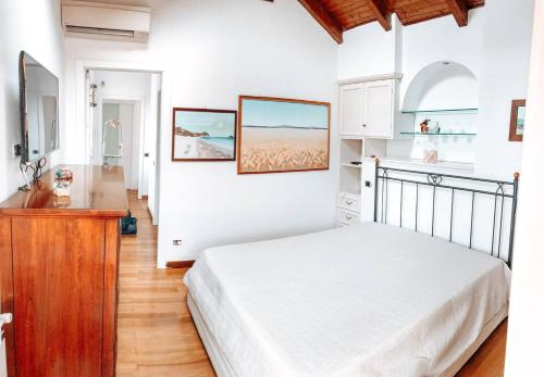 a white bedroom with a bed and a kitchen at La Villa di Bambi in Vanzago