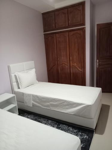 a bedroom with two beds and a cabinet at Résidence Jannat in Ouarzazate