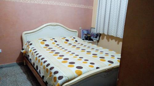 een bed met een polka dot deken erop bij Appartement 05 in Temara