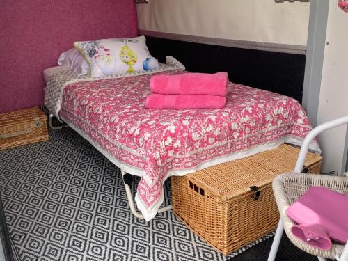 a small bedroom with a bed with pink sheets at Glamping with a twist in Charlton