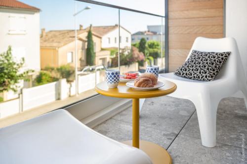 a table and a chair on a balcony with a plate of food at SOUTH-OF-FRANCE T2 neuf haut de gamme, climatisé, parking gratuit, 2eme ligne balcon 3 in Carnon-Plage