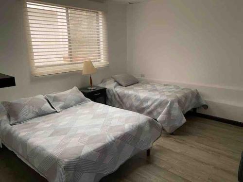 2 Betten in einem Zimmer mit Fenster und einem Bett sidx sidx sidx sidx in der Unterkunft Departamento entero sector Oro Verde in Cuenca