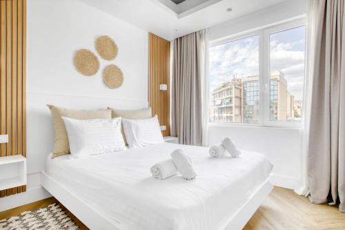 ein weißes Schlafzimmer mit einem großen weißen Bett mit Handtüchern darauf in der Unterkunft Kallirrois 89 Suite in Athen
