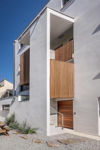 a facade of a house with a wooden door at SOUTH-OF-FRANCE T2 neuf haut de gamme, climatisé, parking gratuit, 2eme ligne balcon 3 in Carnon-Plage