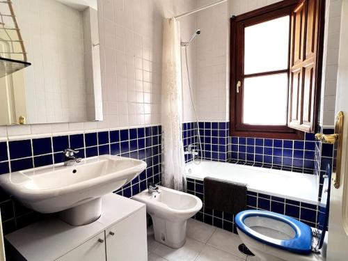 La salle de bains bleue et blanche est pourvue d'un lavabo et de toilettes. dans l'établissement Apartamento muy céntrico en Granada, à Grenade