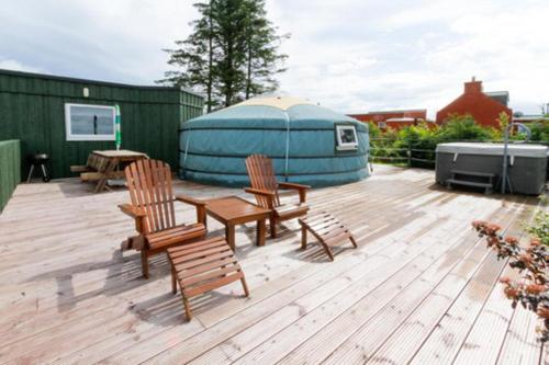 a deck with chairs and a table and a yurt at Green Yurt with Hot Tub - Sleeps 3 Parking & WiFi in Turriff
