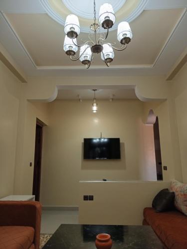a living room with a chandelier and a tv at Résidence Jannat in Ouarzazate
