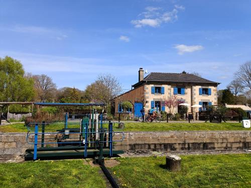 un parc avec une aire de jeux en face d'une maison dans l'établissement Ille Flottante, Maison éclusière et hébergements insolites sur le canal, à Hédé