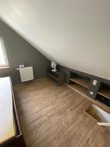 an attic room with a staircase and wooden floors at Le doux refuge in Bouillon