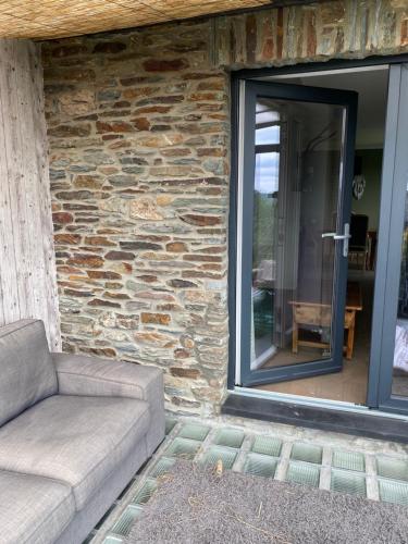 a couch sitting in front of a stone wall at Le doux refuge in Bouillon