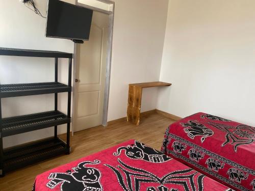 a room with a bed and a stool and a television at Buena Vista Lobitos in Lobitos