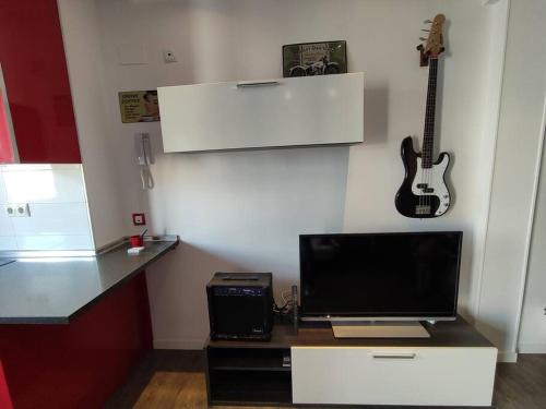 - un salon avec une télévision et une guitare sur le mur dans l'établissement Amonaren Etxea., à Saint-Sébastien