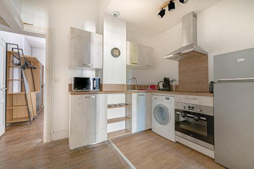 a kitchen with white cabinets and a washer and dryer at Le pied à terre d'ernest in Limoges