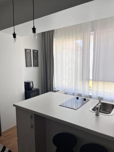 uma cozinha com um balcão branco e uma janela em Stilingi šaulio skulptūros apartamentai em Druskininkai