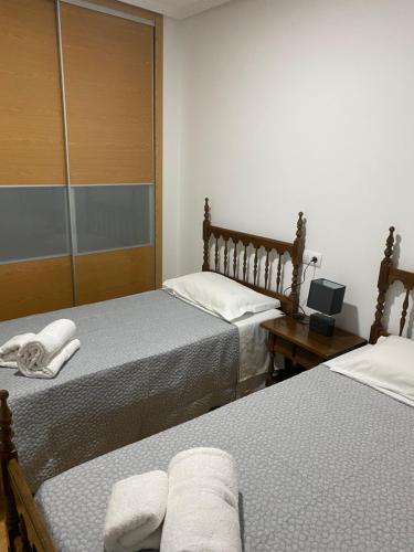 a bedroom with two beds and a desk with a laptop at Apartamento Duplex O capitán in A Guarda