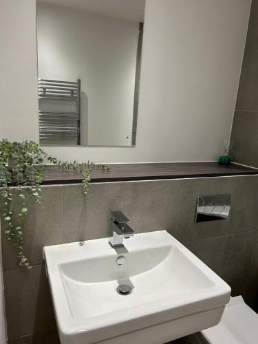 a bathroom with a white sink and a mirror at Modern 2BR Sleeps 4 Easy Access to City Centre in Manchester