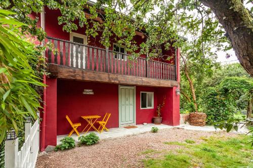 a red house with a balcony and a table at Caserío El Ronzón in Camoca de Abajo