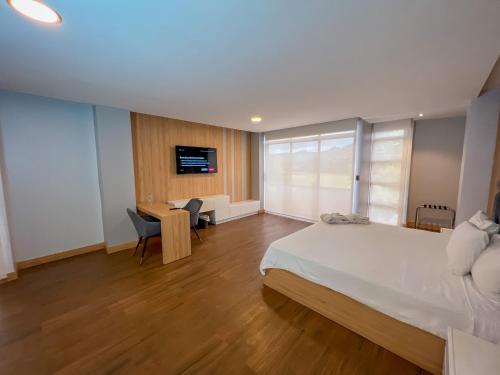 a bedroom with a bed and a desk and a tv at Arhaná Hosteria & Resort in Gualaceo