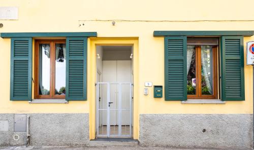a yellow building with green shutters and a door at Appartamenti Empoli-Vinci in Empoli