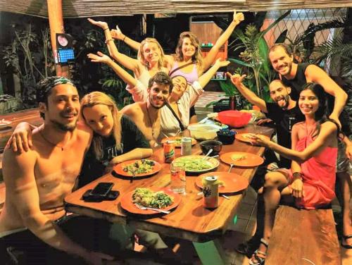um grupo de pessoas sentadas à volta de uma mesa em Hostel Mariposas em Sámara