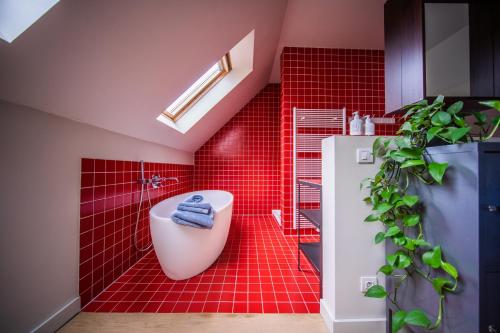 a red tiled bathroom with a toilet and a plant at Casa Mina - Dok Noord Ghent in Ghent