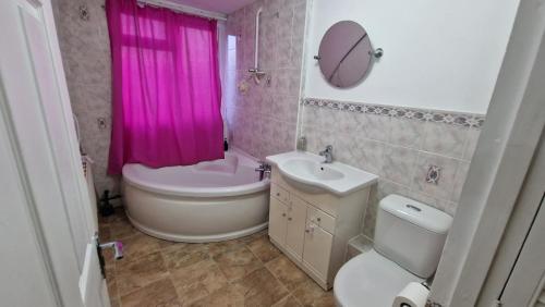 y baño con lavabo, aseo y cortina de ducha rosa. en Rooms Shared Kitchen FREE Parking, en Slough
