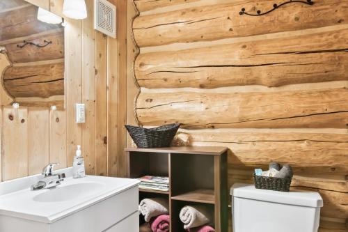 baño con lavabo blanco y pared de madera en Chum Salmon, en Soldotna