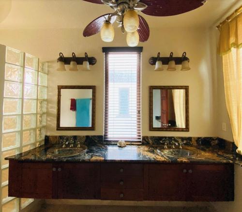 a bathroom with two sinks and two mirrors at Beach Front Condo steps from beach in Six Huts