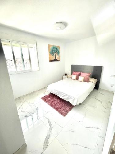 biała sypialnia z łóżkiem z różowymi poduszkami w obiekcie Apartamento Benidorm Rincón de Loix w mieście Benidorm
