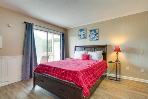 ein Schlafzimmer mit einem Bett mit einer roten Bettdecke und einem Fenster in der Unterkunft New River Gorge Vacation Rental with Balcony! in Fayetteville