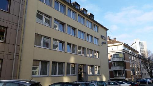 un edificio alto con coches estacionados frente a él en Luise City - An der Philharmonie, en Essen