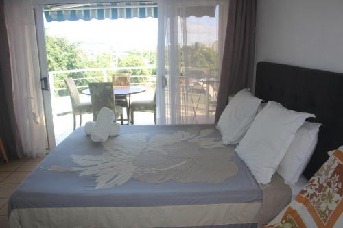 um quarto com uma cama e vista para uma varanda em Régent 4e étage em Papeete