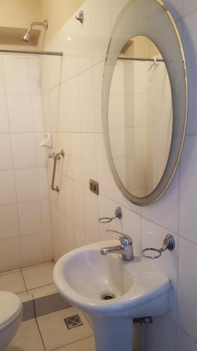 a bathroom with a sink and a mirror and a toilet at Hotel Maison Fiori Prado in Cochabamba