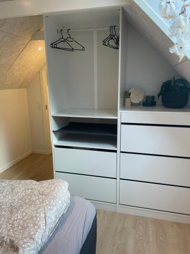 a bedroom with a white closet with white drawers at Lejlighed i naturskønt område in Silkeborg