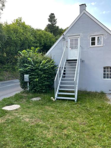 a white house with a staircase next to a street at Lejlighed i naturskønt område in Silkeborg