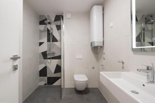 a white bathroom with a toilet and a sink at Superior Seaview Apt. with Pool in Umag